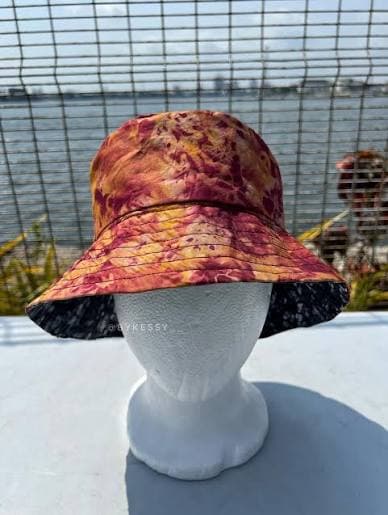 Rust and gold batik Adire bucket hat on a white mannequin head