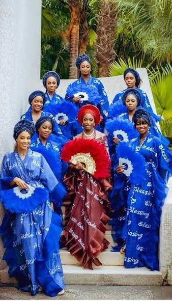 Bride's party in royal blue Adire gowns with white Blessing lettering