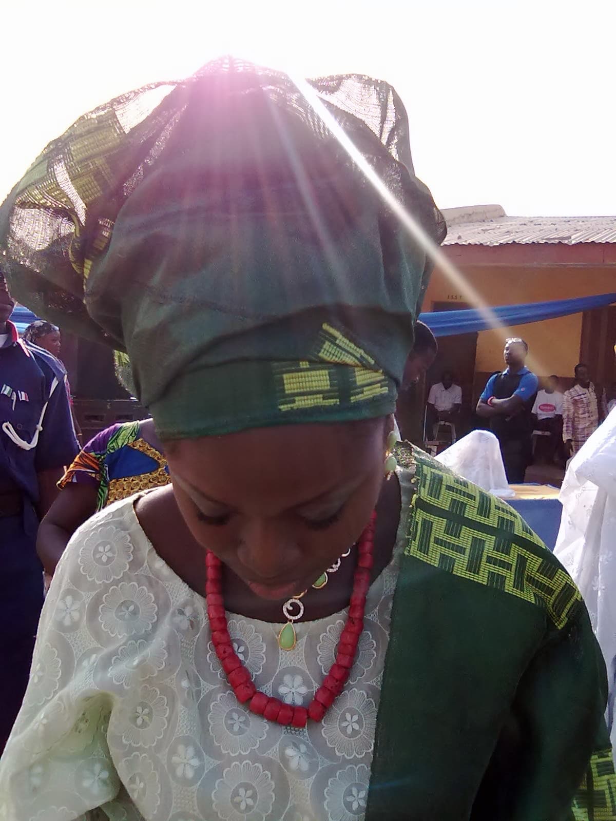 Bride in a lace buba with an emerald Aso Oke gele and ipele