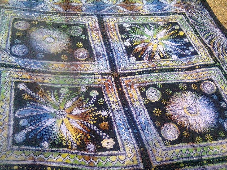 Adire fabric with four starburst panels in blue, gold and green on black